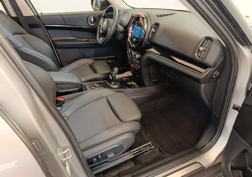 Intérieur côté passager de la MINI Countryman gris foncé 2023, avec tableau de bord et sièges en cuir noir.
