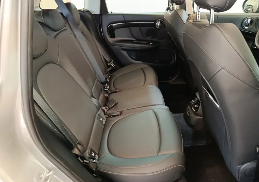 Vue intérieure côté gauche des sièges arrière en cuir noir du MINI Countryman 2023, avec ceinture de sécurité et garnitures de porte visibles.
