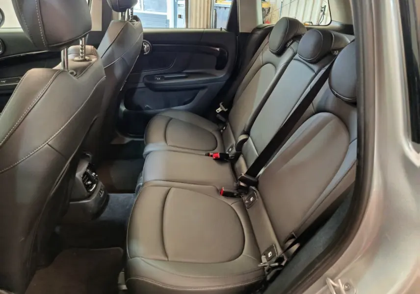 Vue intérieure côté droit des sièges arrière en cuir noir du MINI Countryman gris foncé 2023, avec appuie-têtes et ceintures visibles.