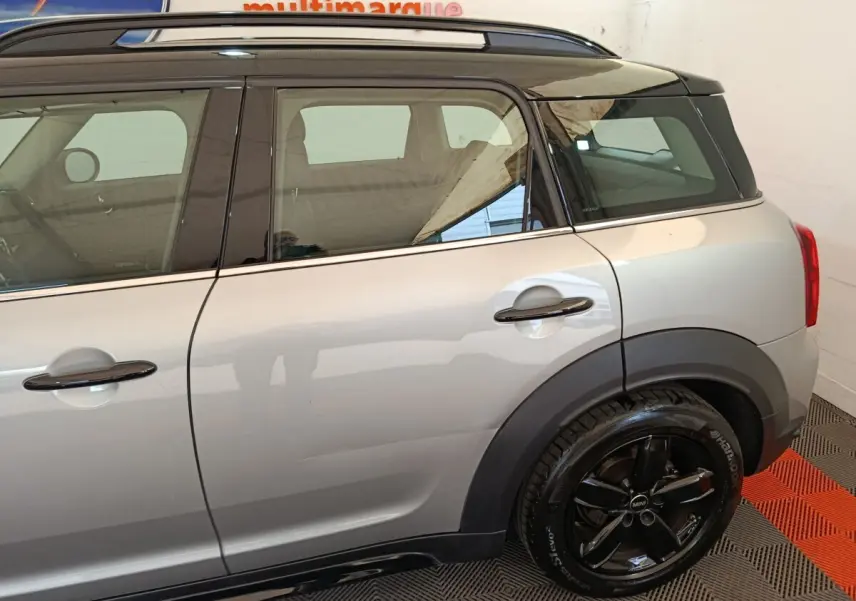 Vue latérale droite sur l'arrière d'une MINI Countryman gris foncé avec toit noir et jantes noires brillantes.