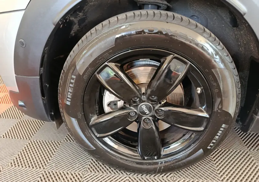 Gros plan sur la roue avant gauche noire brillante d'une MINI Countryman gris foncé avec pneu Pirelli visible.