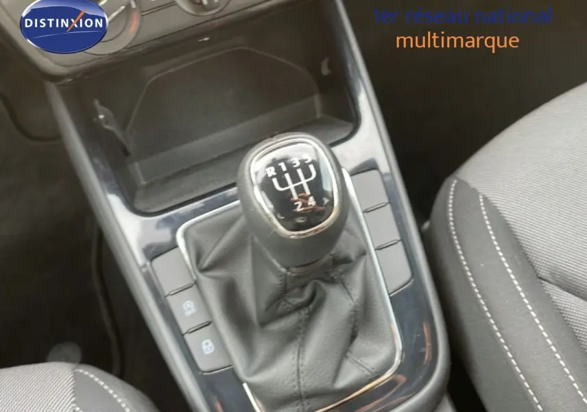 Gros plan sur le levier de vitesse manuel en cuir noir de la Skoda Fabia blanc glacier, avec console centrale et siège tissu gris.