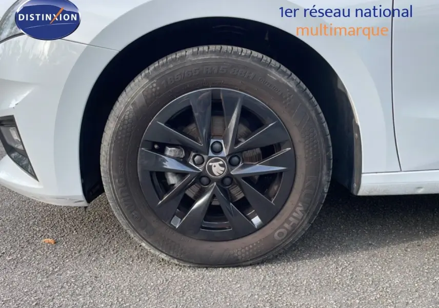 Gros plan sur la roue avant gauche noire d’une Skoda Fabia blanc glacier, soulignant la jante au design moderne.