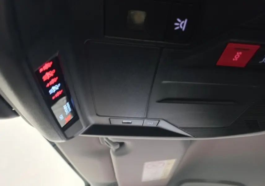Vue intérieure en gros plan du panneau de commandes au plafond avec bouton SOS rouge dans une Peugeot 308 bleu.