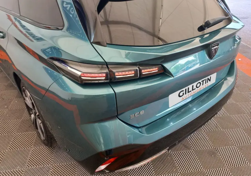 Vue 3/4 arrière droite d'une Peugeot 308 bleu avec feux arrière LED et logo Peugeot visible sur le hayon.