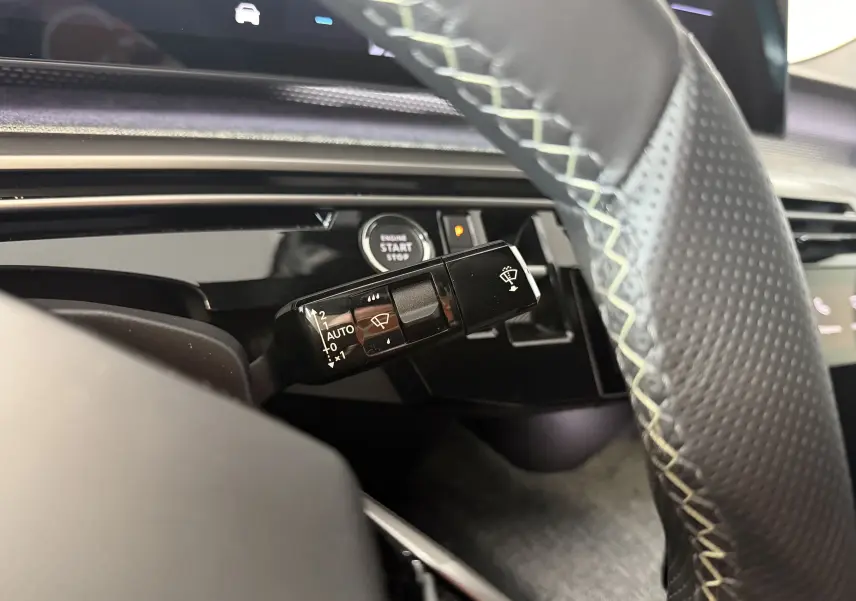 Gros plan sur la commande d’essuie-glace à gauche du volant perforé dans l’habitacle du Peugeot 3008 Hybrid 145 GT 2025.