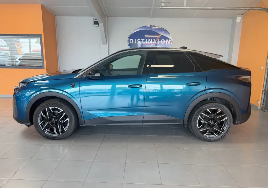 Vue latérale droite d’un Peugeot 3008 Hybrid 145 GT bleu Obsession avec toit noir et jantes alliage 19 pouces en intérieur showroom.