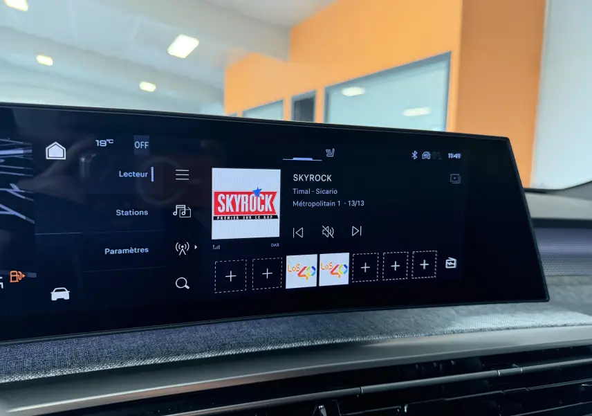 Écran tactile central du tableau de bord du Peugeot 3008 Hybrid, affichant la radio Skyrock en intérieur lumineux.