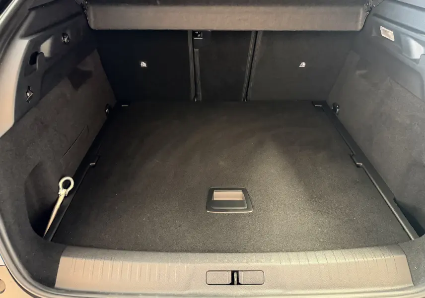 Vue intérieure du coffre spacieux du Peugeot 3008 Hybrid 145 GT, avec revêtement noir et hayon ouvert.