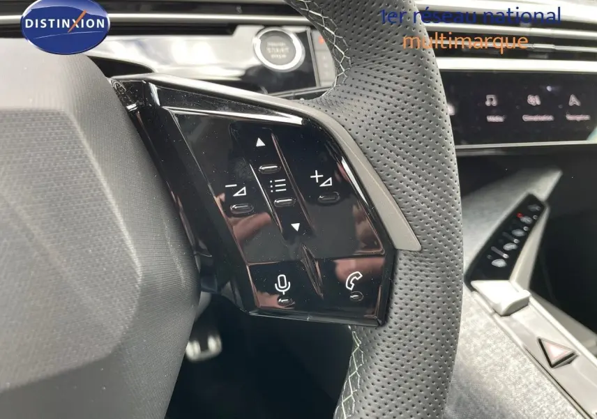 Gros plan sur la commande gauche du volant cuir perforé du Peugeot 5008 Hybrid blanc Okenite 2025 avec tableau de bord moderne.