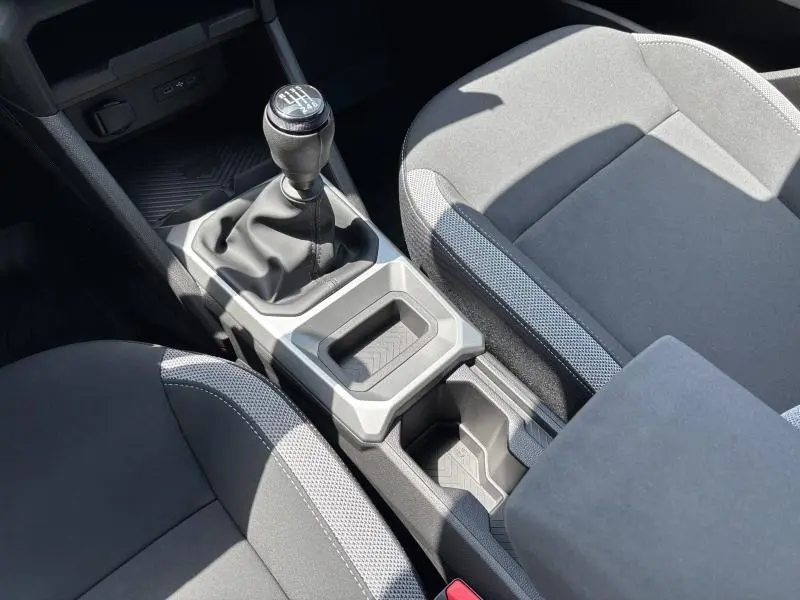 Vue rapprochée de la console centrale intérieure du Dacia Bigster blanc, avec levier de vitesse manuel et sièges tissu gris.