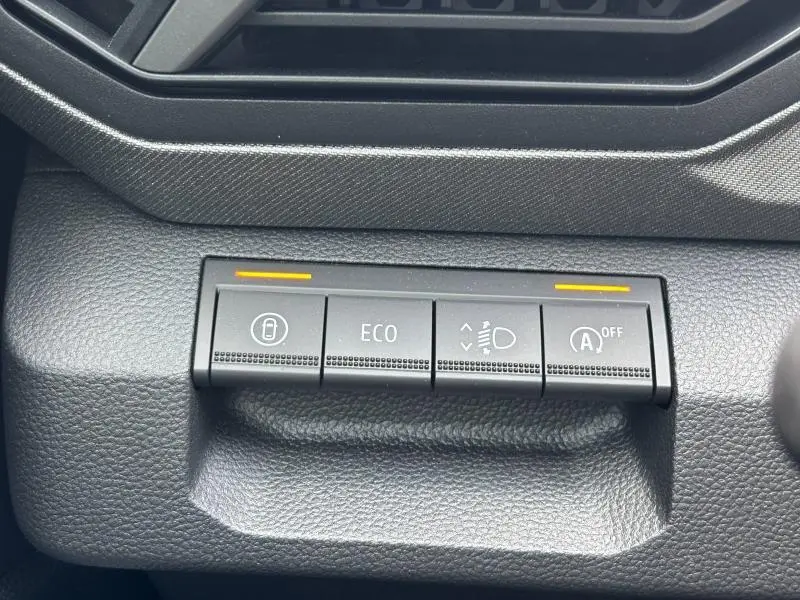 Gros plan sur les boutons de commande du mode ECO et des phares du tableau de bord du Dacia Bigster blanc.