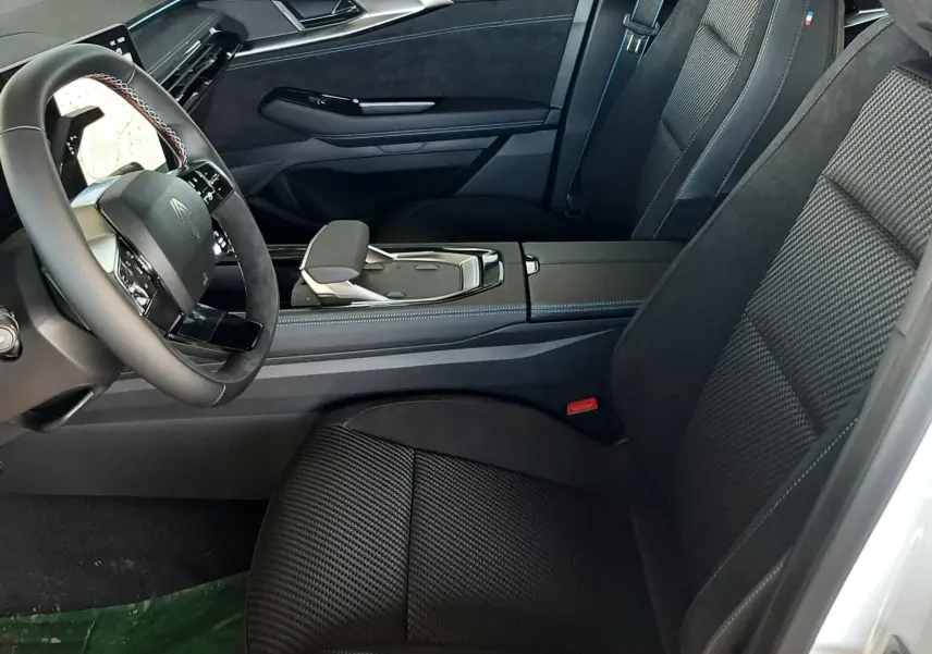 Vue intérieure côté conducteur du Renault Austral 2025, sièges noirs avec surpiqûres blanches et console centrale moderne.