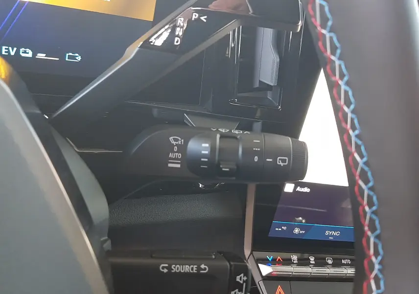 Gros plan sur la commande de boîte automatique et les commandes au volant du Renault Austral E-Tech blanc nacré, intérieur noir avec surpiqûres tricolores.