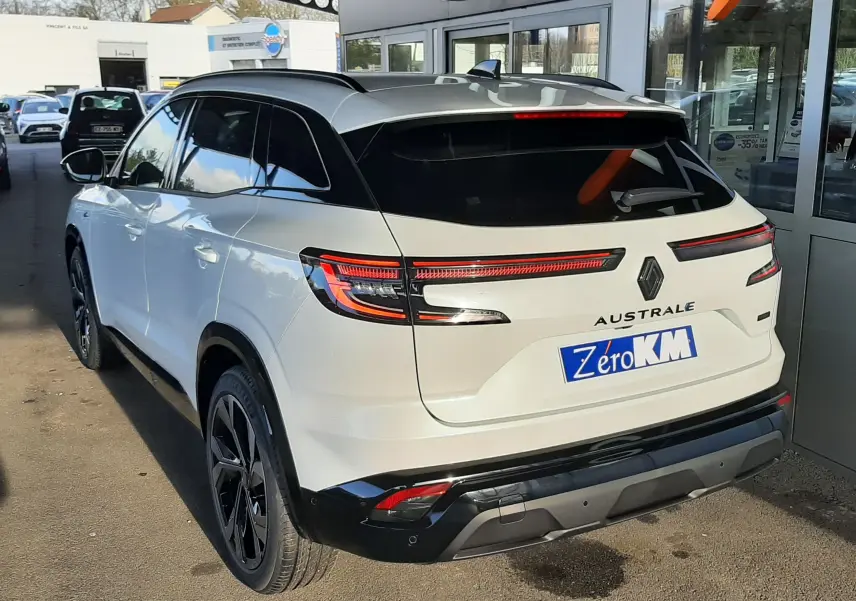 Vue 3/4 arrière droite du Renault Austral blanc nacré avec toit noir, feux arrière LED et hayon motorisé visible.