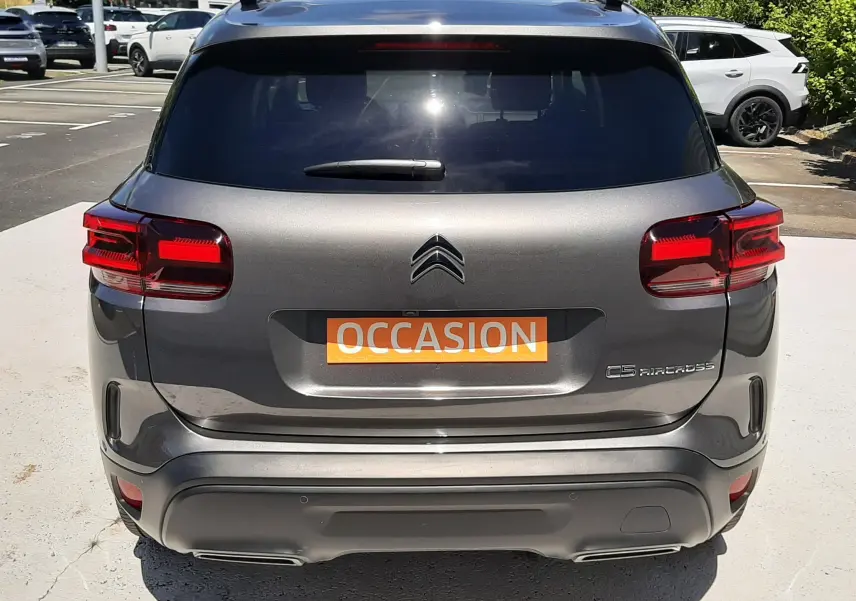 Vue arrière d'un Citroën C5 Aircross hybride gris platinium, avec feux rouges et plaque "OCCASION" visible.