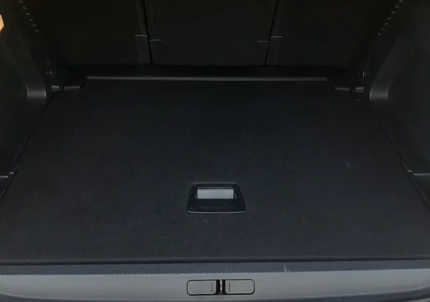 Coffre ouvert vu de l'arrière d'un Citroën C5 Aircross hybride gris platinium, espace de chargement vide et propre.