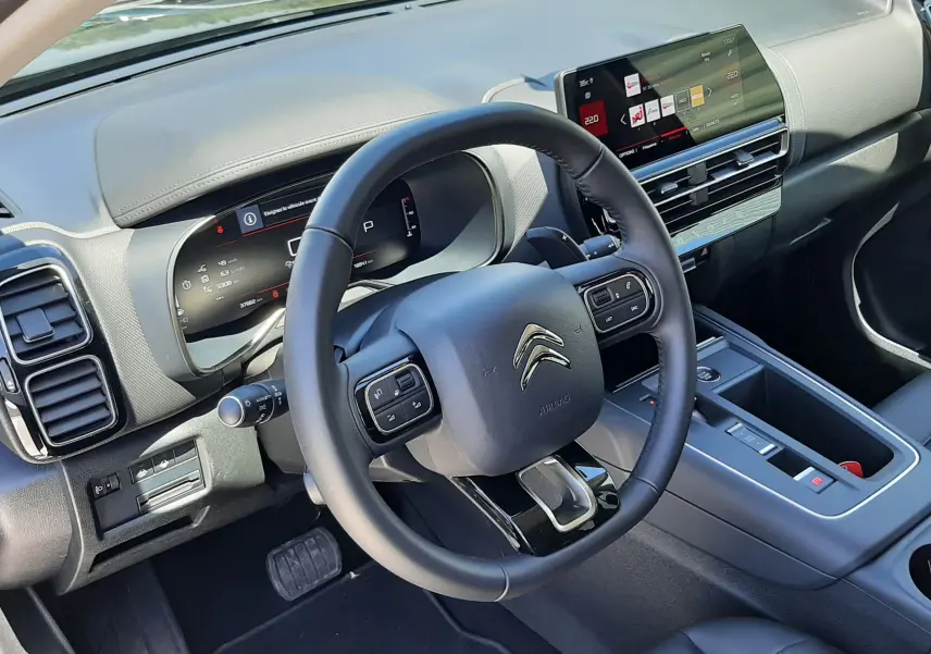 Vue intérieure côté conducteur du Citroën C5 Aircross hybride 2025 avec tableau de bord numérique et volant multifonction noir.