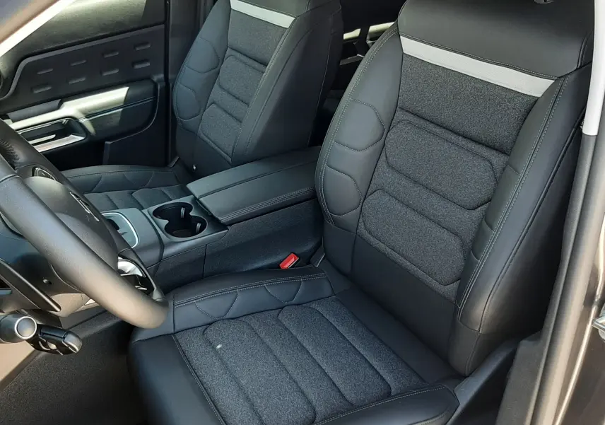 Vue intérieure côté conducteur du Citroën C5 Aircross hybride 2025, sièges bi-matière noir et gris, console centrale avec accoudoir.