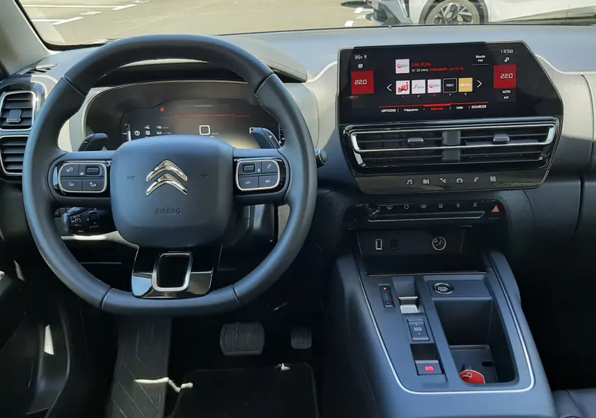 Vue intérieure centrée sur le volant et la console centrale du Citroën C5 Aircross hybride 2025, avec écran tactile et finitions noires.
