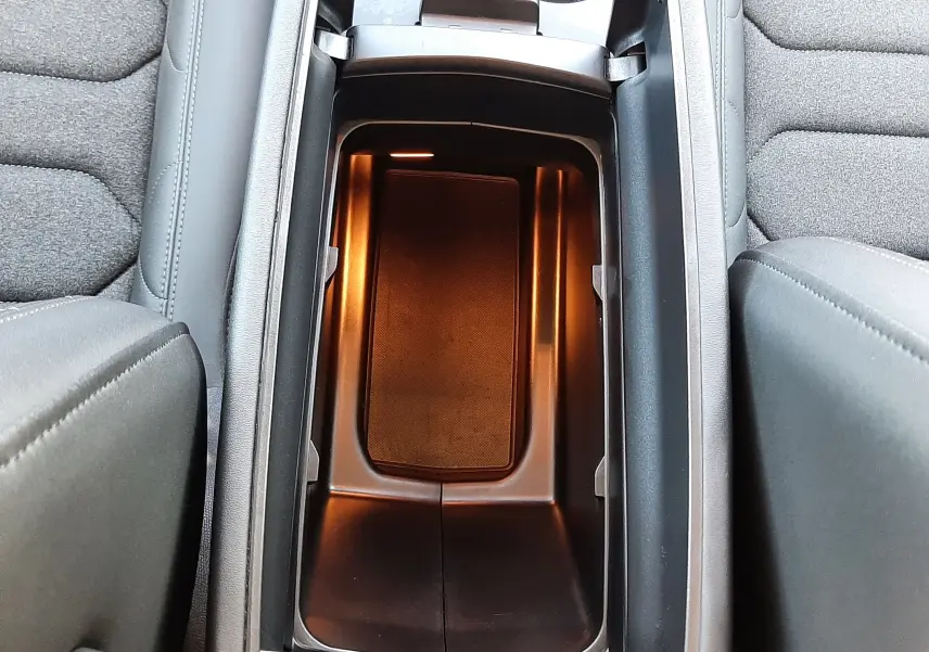 Vue plongeante sur le rangement central éclairé et les sièges gris tissu du Citroën C5 Aircross hybride 2025.