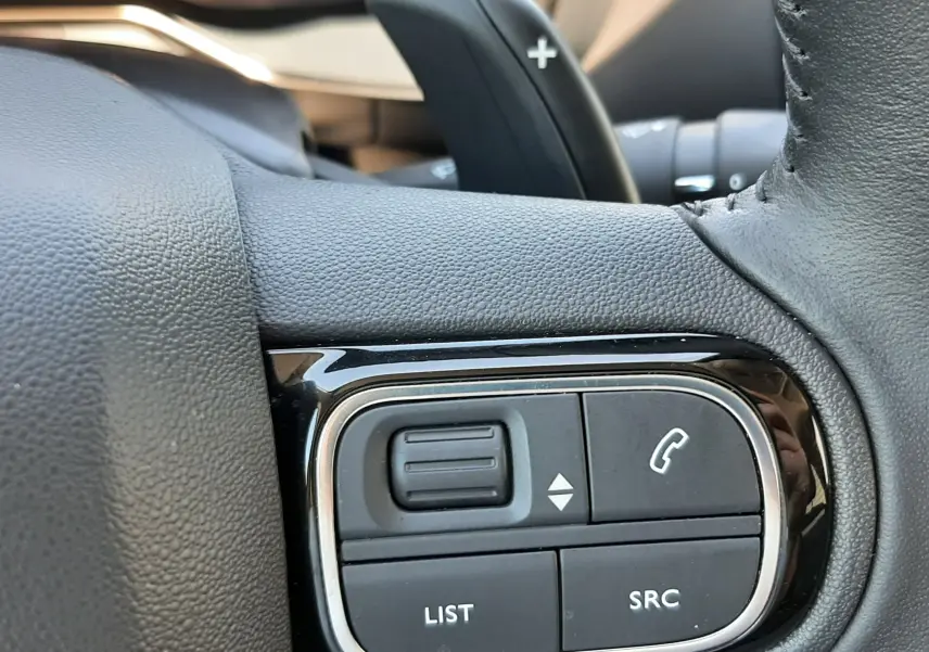 Gros plan sur les commandes multifonctions noires du volant du Citroën C5 Aircross hybride 2025.