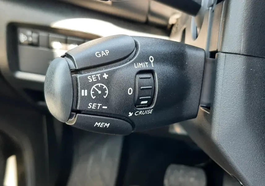 Gros plan sur la commande de régulateur de vitesse noire dans l'habitacle du Citroën C5 Aircross gris platinium 2025.