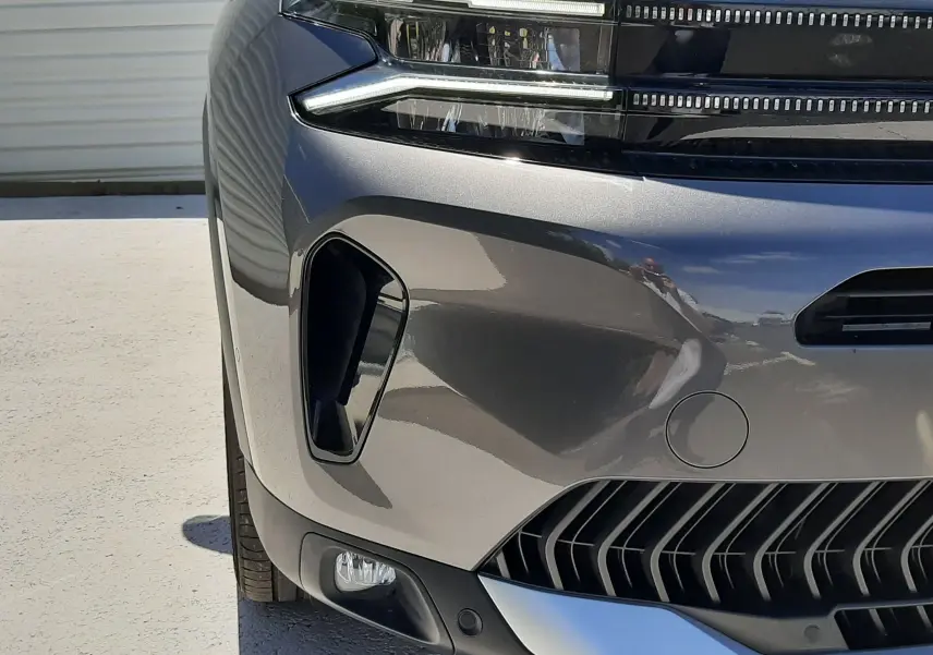 Gros plan sur l'avant gauche du Citroën C5 Aircross hybride gris platinium, mettant en valeur ses phares LED et la calandre distinctive.