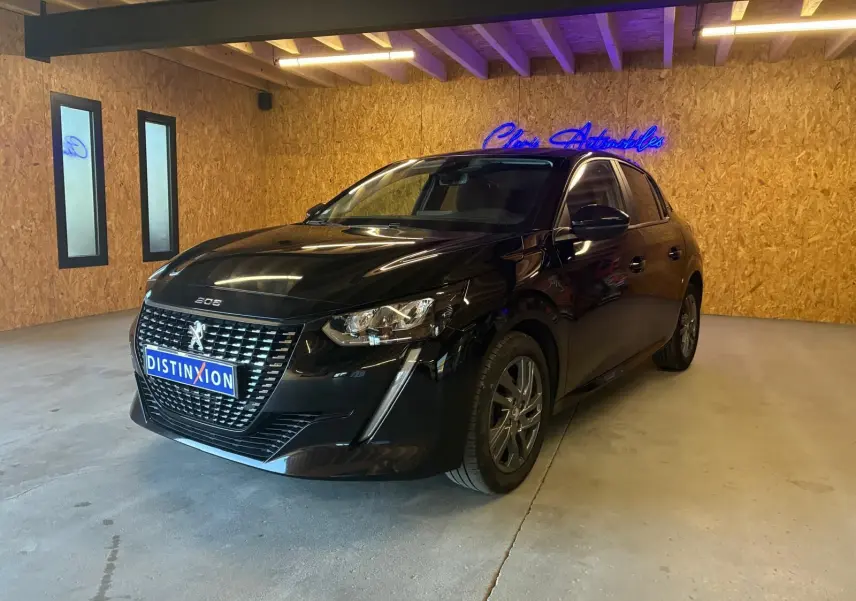 Peugeot 208 1.5 BlueHDi 100 Style noir vue 3/4 avant droit dans un garage avec mur en bois.