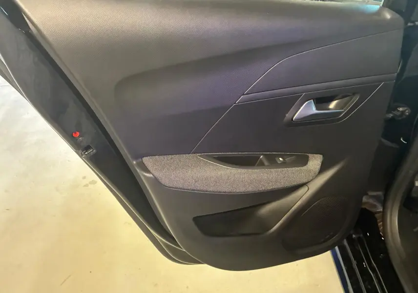 Vue rapprochée de la porte arrière gauche intérieure noire de la Peugeot 208 1.5 BlueHDi 100 Style avec tissu gris.