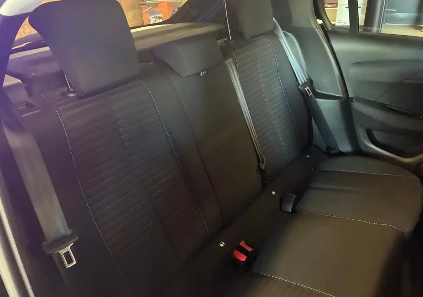 Vue intérieure de la banquette arrière noire en tissu de la Peugeot 208 1.5 BlueHDi 100 Style, avec ceintures visibles.