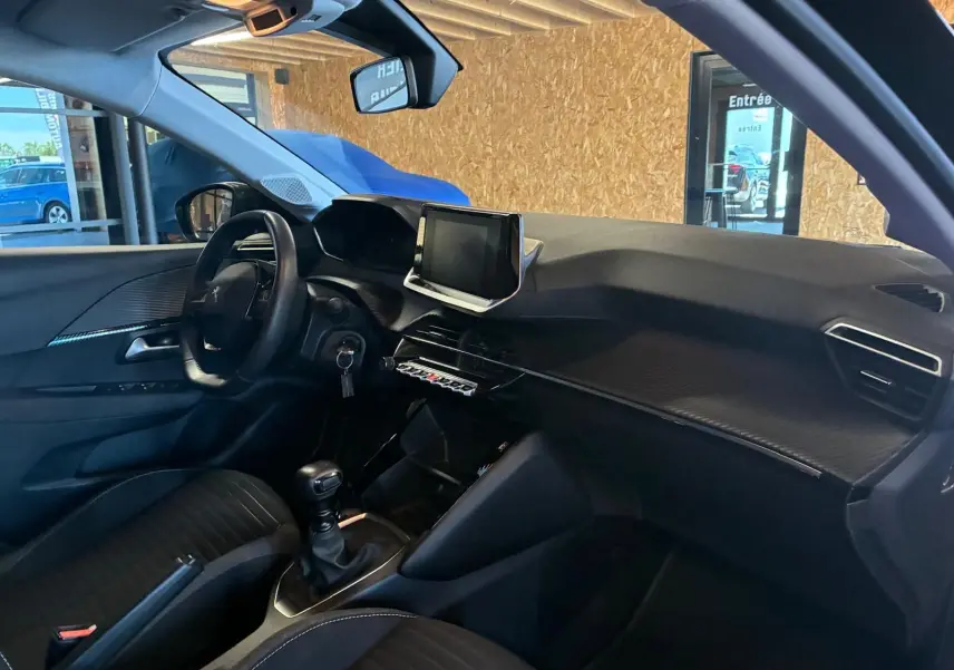 Vue intérieure côté conducteur de la Peugeot 208 1.5 BlueHDi 100 Style 2021 avec tableau de bord noir et écran tactile central.