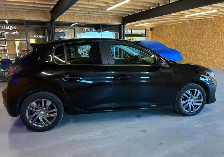 Peugeot 208 1.5 BlueHDi 100 Style noir vue de profil côté gauche dans un garage avec intérieur tissu noir.