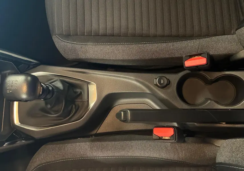 Vue intérieure en plongée sur la console centrale de la Peugeot 208 noire, montrant levier de vitesse manuel et frein à main.