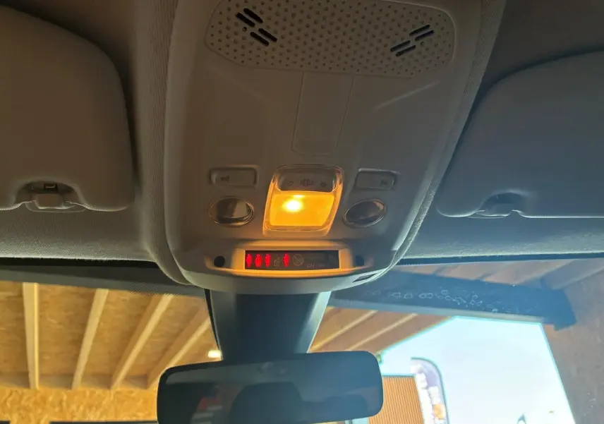 Plafonnier allumé vu de l’intérieur avant d’une Peugeot 208 noire 1.5 BlueHDi 2021 avec rétroviseur central.