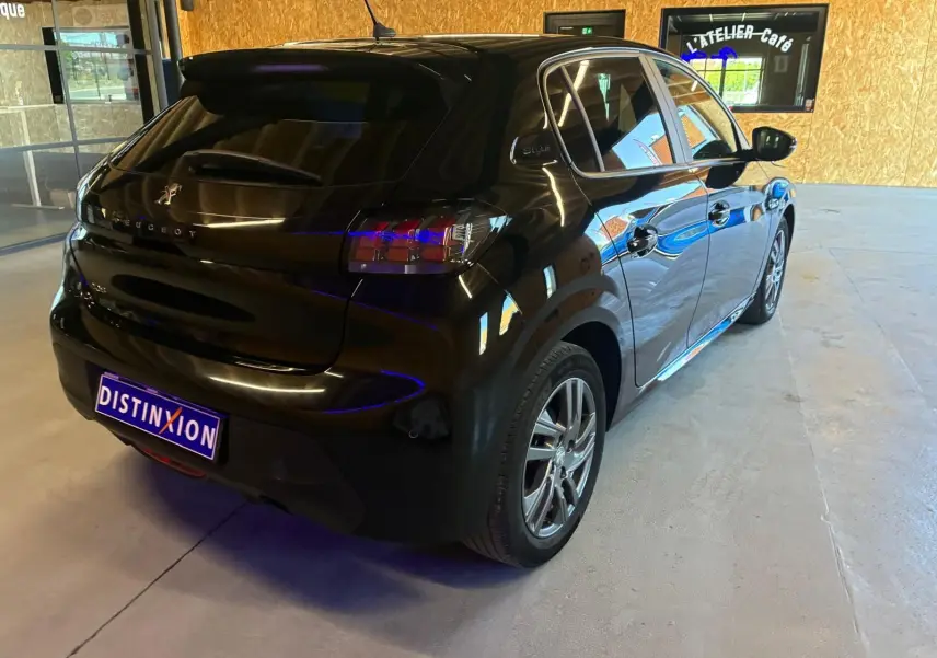 Vue 3/4 arrière droite d'une Peugeot 208 noire 5 portes, avec feux arrière distinctifs et jantes alliage en intérieur clair.