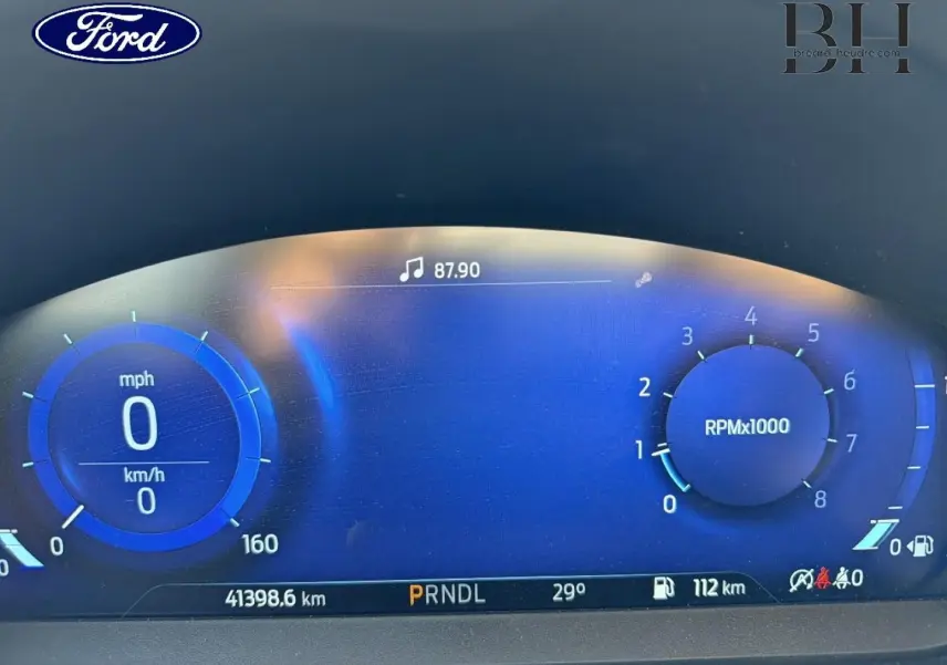 Tableau de bord numérique de Ford Focus 2023 affichant vitesse, compte-tours, température et autonomie, éclairage bleu.