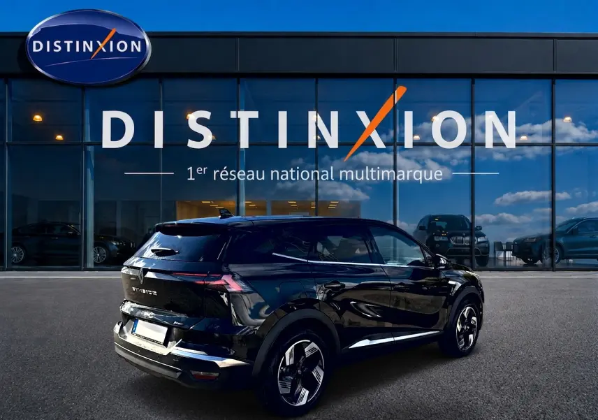 Vue 3/4 arrière droite d’un Renault Symbioz noir étoile avec jantes alu, garé devant une vitrine Distinxion.