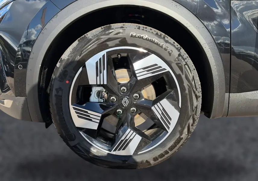 Gros plan sur la roue avant gauche noire étoile d'une Renault Symbioz 1.8 e-tech avec jante alu à motifs géométriques.