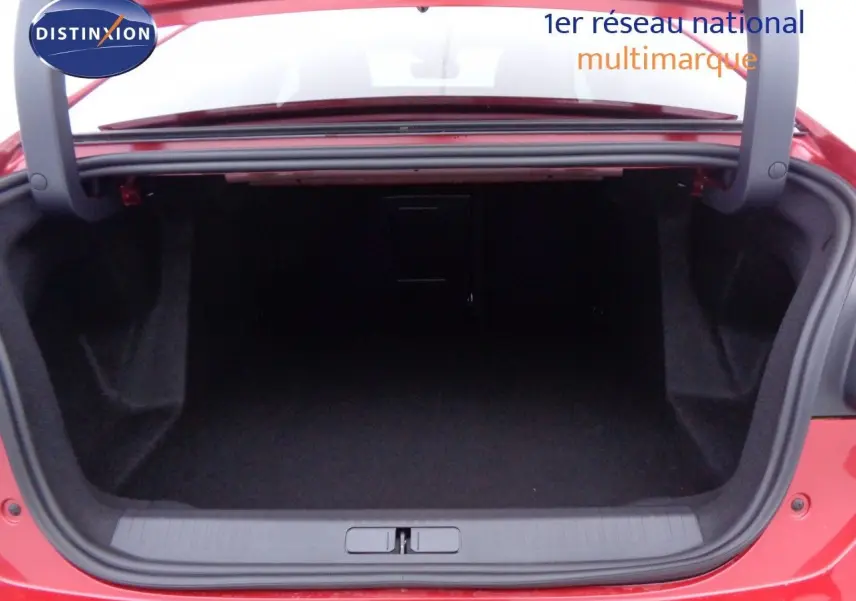 Coffre ouvert vu de l'arrière d'une Citroën C4 X rouge Elixir Métal, montrant l'espace de chargement vide.