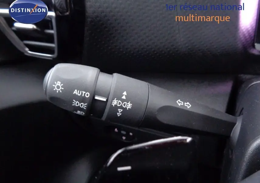 Gros plan sur la commande des phares et clignotants à gauche du volant dans l’habitacle d’une Citroën C4 X rouge Elixir Metal.