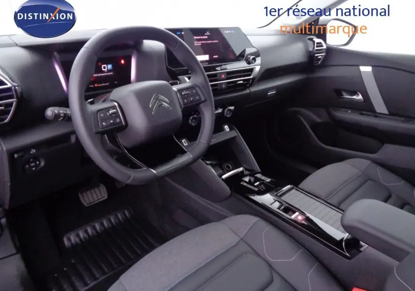 Intérieur de la Citroën C4 X 2023, vue du poste de conduite côté gauche, avec tableau de bord numérique et console centrale noire brillante.