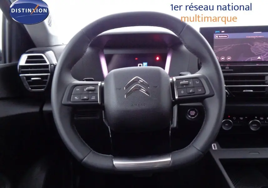 Vue rapprochée du volant noir du Citroën C4 X 2023 avec commandes intégrées et tableau de bord numérique.