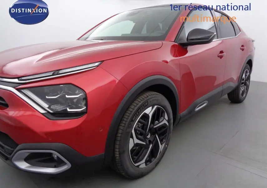 Vue 3/4 avant droit d'une Citroën C4 X rouge Elixir métal avec jantes bicolores et détails noirs contrastants.