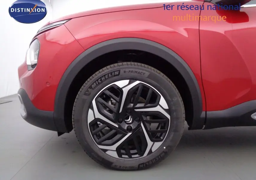 Gros plan sur la roue avant gauche d'une Citroën C4 X rouge Elixir Métal avec jante alliage noire et argent.