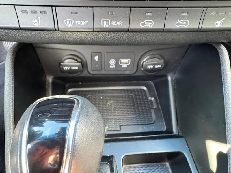 Vue rapprochée de la console centrale du Hyundai Tucson noir montrant levier de vitesses et prises USB et 12V.