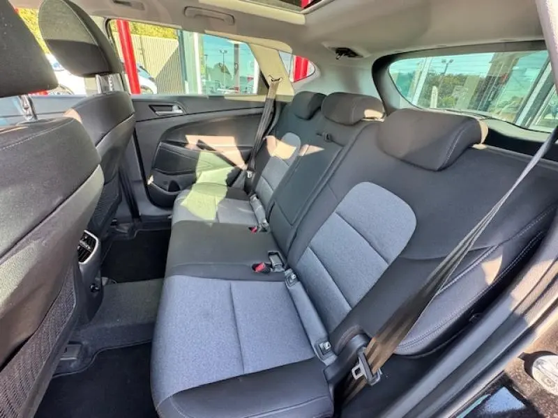 Vue intérieure arrière côté droit du Hyundai Tucson 2019 avec sièges tissu noir et gris et ceintures de sécurité visibles.