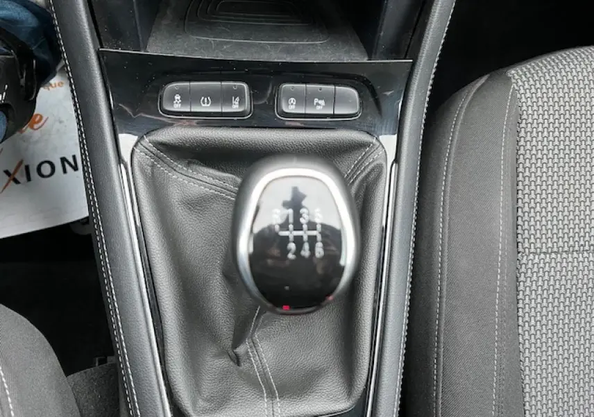 Le levier de vitesse manuel de l'Opel Grandland X 2019, entouré de commandes et siège tissu gris à droite.