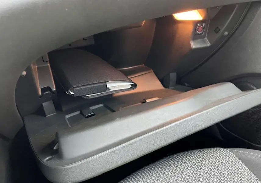 Gant de boîte à gants ouvert avec éclairage intérieur, montrant un carnet noir dans un Opel Grandland X gris clair.