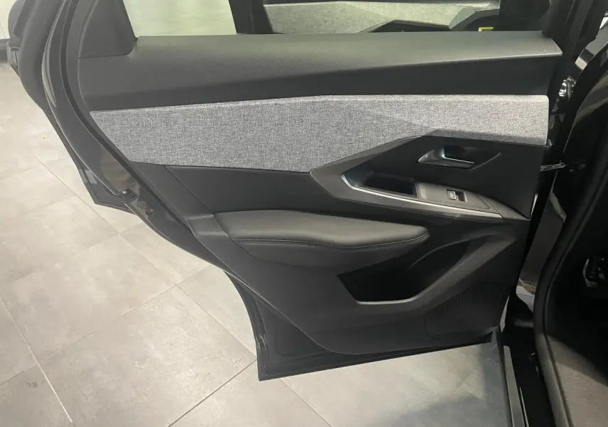 Vue intérieure du panneau de porte arrière gauche du Peugeot 3008 GT 2025 noir métallisé avec insert tissu gris et commandes de fenêtre.